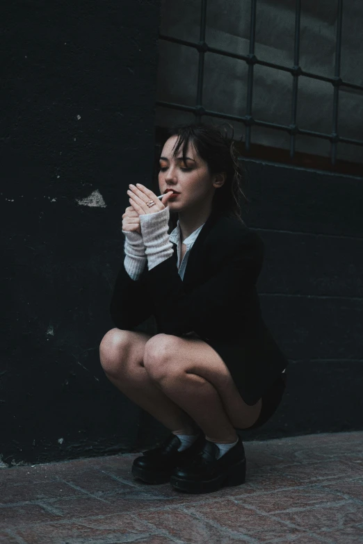 a woman squats on the ground and holds her hand over her mouth