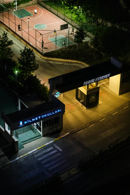 a lit up basketball court next to a park