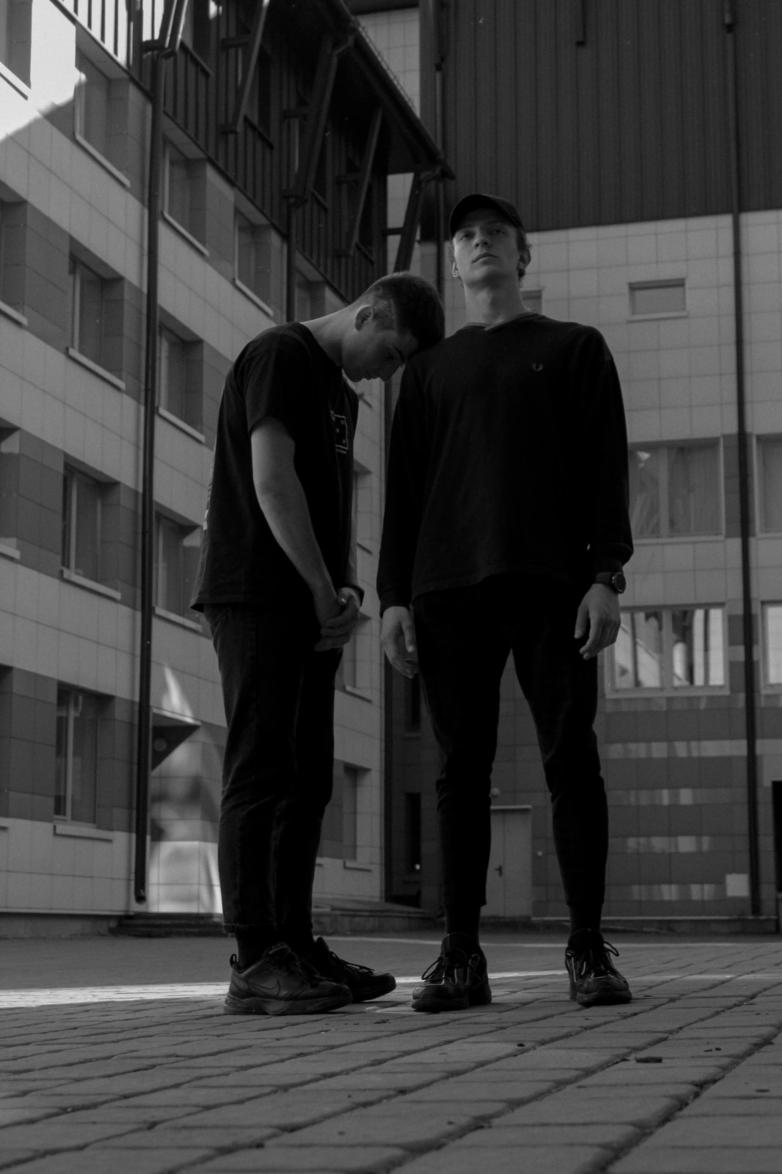 two young men stand side by side in front of a large building