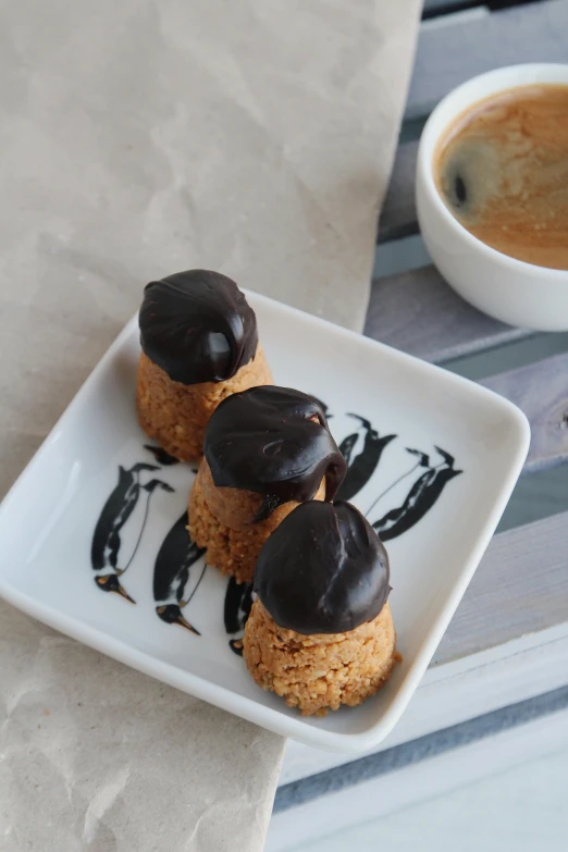 small desserts are served on a plate next to a cup of coffee