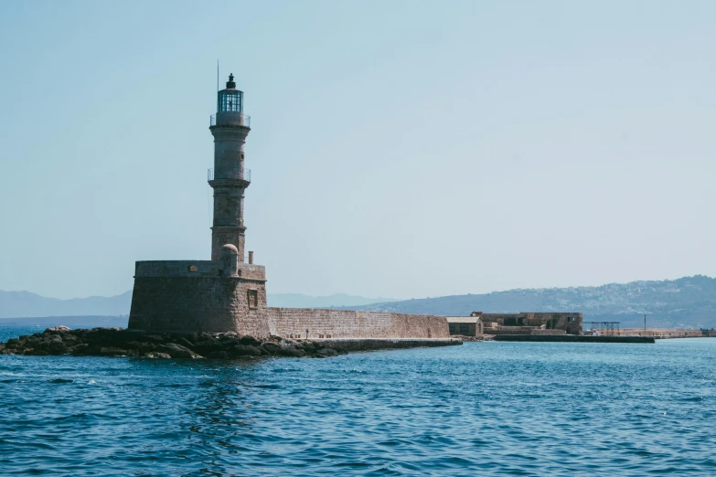 a light house sits on a rock outcropping in the ocean