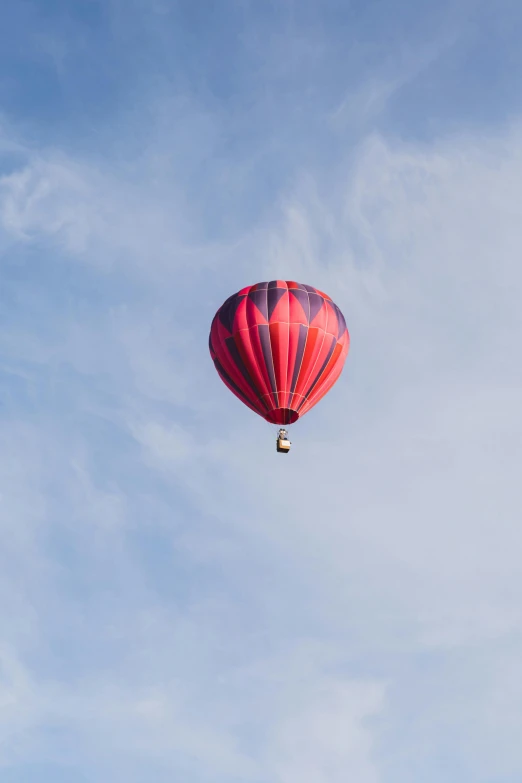 a red  air balloon flying high in the sky