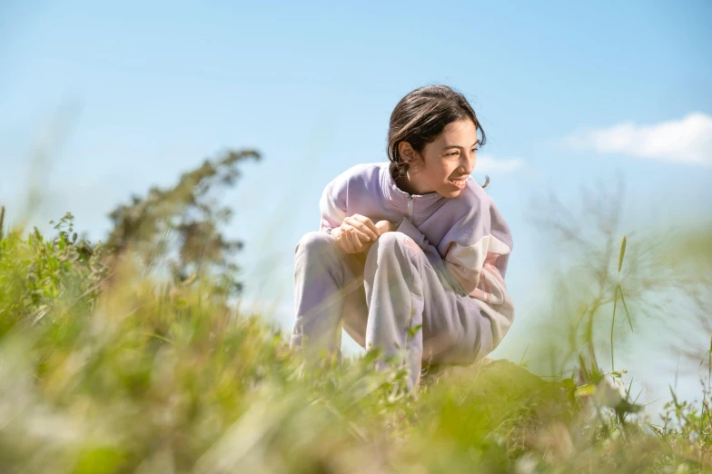 a woman is sitting on the grass with her head in her hands