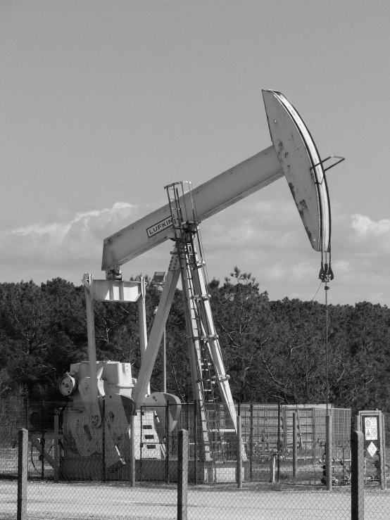 an oil rig with a fence and trees