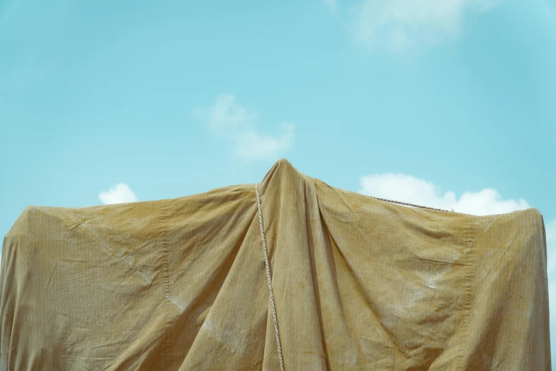 an overhanging tan colored fabric with blue sky background