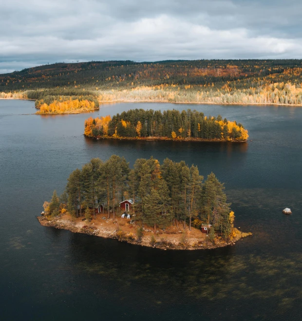 two tiny houses on an island, surrounded by trees