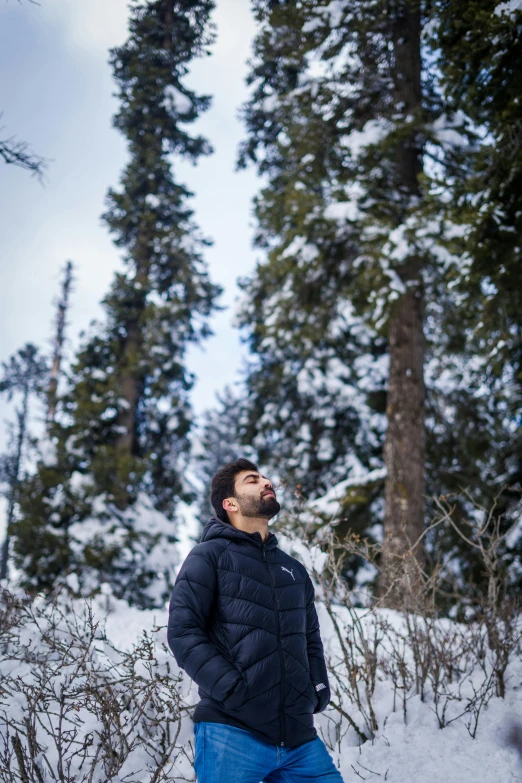 a bearded man standing in the snow among a forest