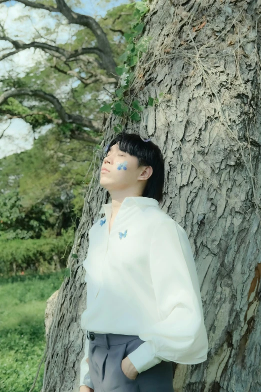 a girl with blue paint on her face standing near a tree