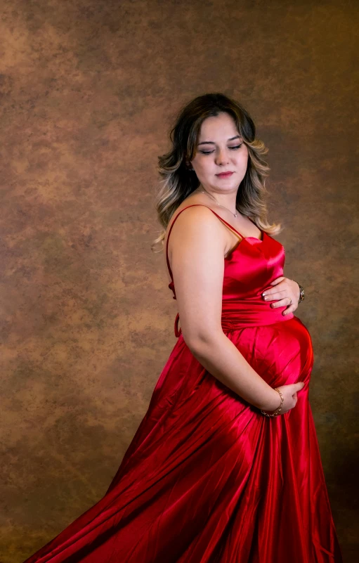 a pregnant woman in a red dress poses for a pograph