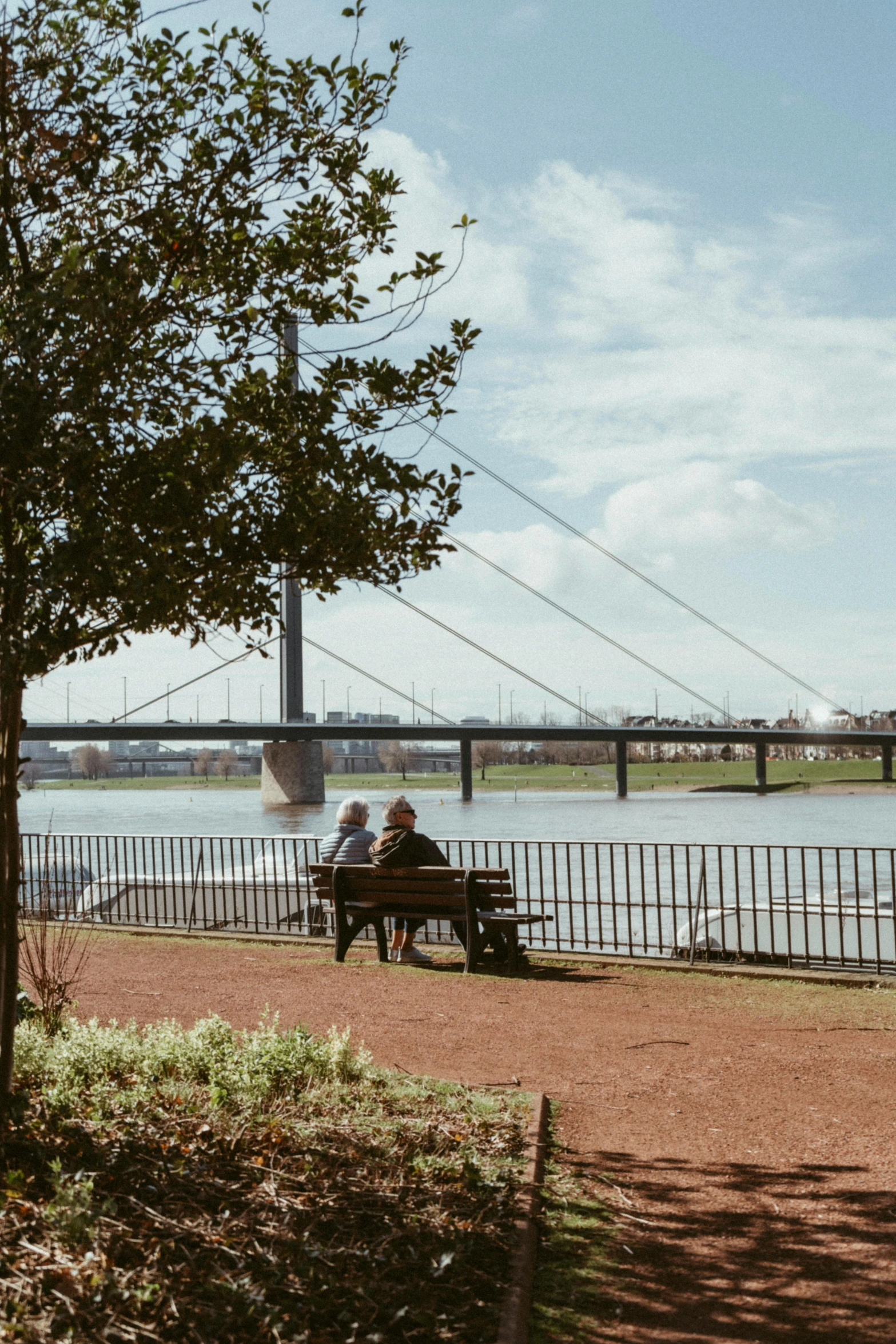 two people sit on a park bench near a lake