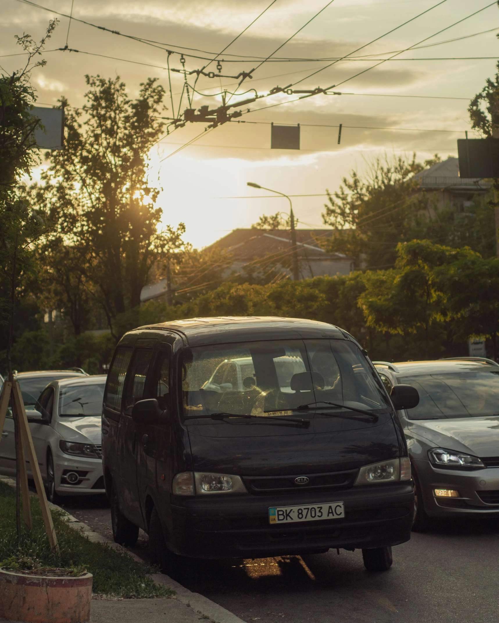 a black van parked at the curb next to some parked cars