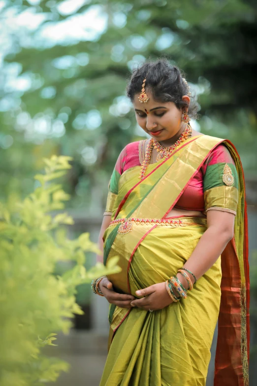 a pregnant woman wearing a yellow sari