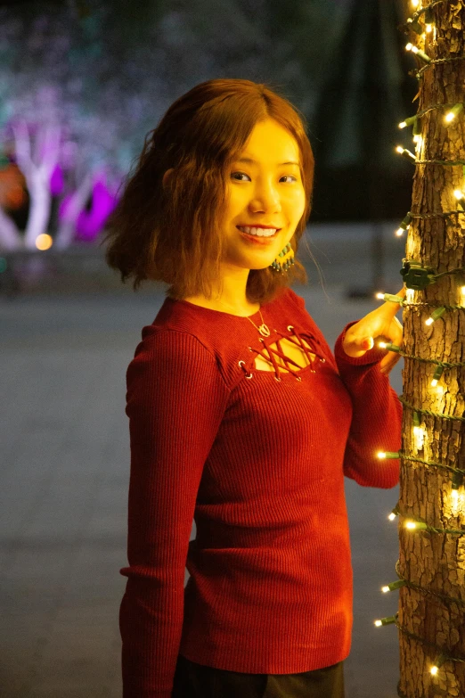 a beautiful young woman posing with some christmas lights