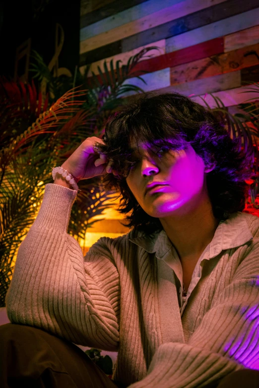 a woman sits and poses near an indoor plant