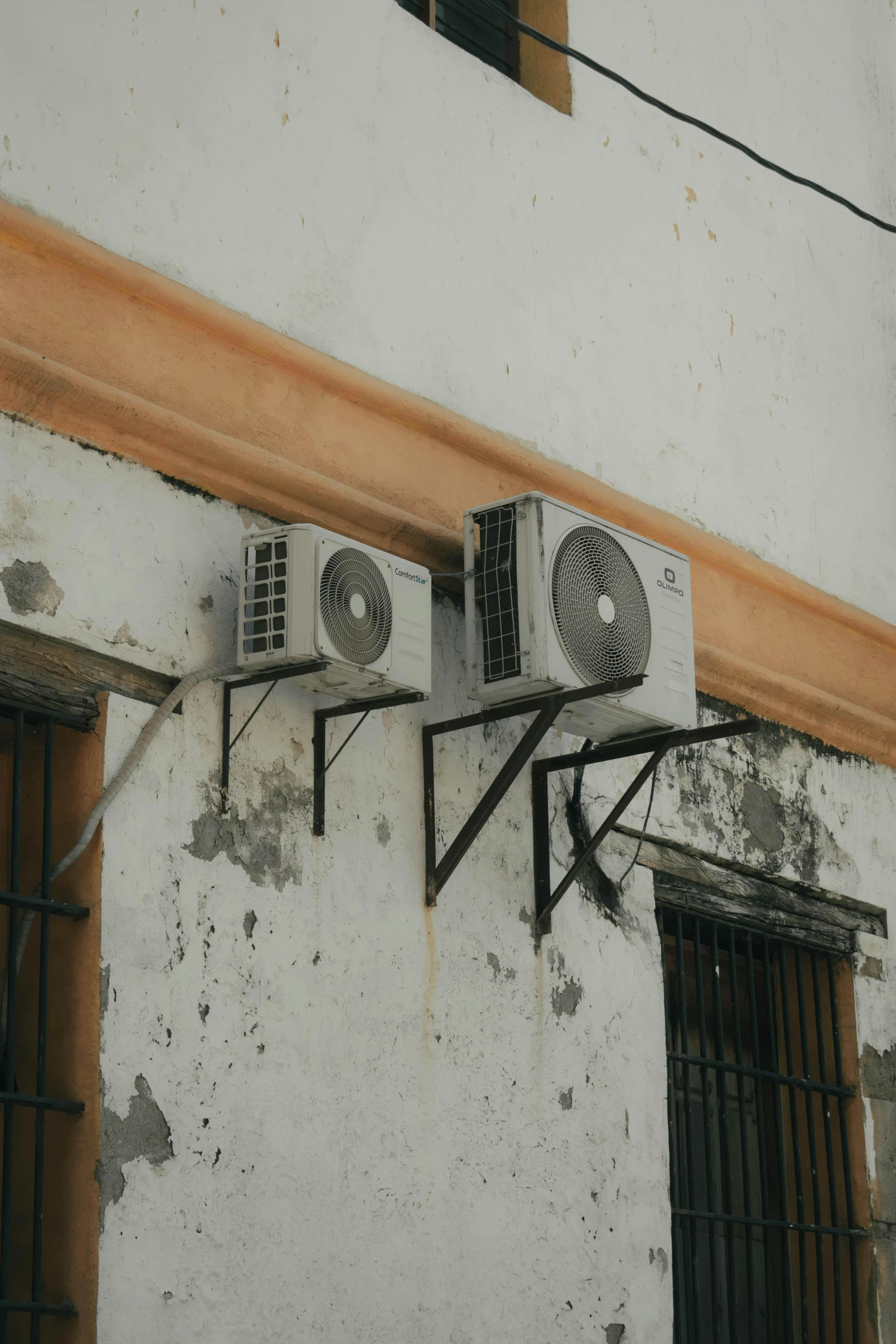 some dirty air conditioners mounted on the side of a building