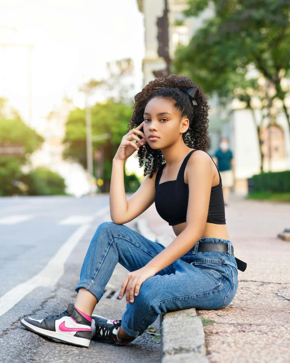 a girl sitting on the ground while talking on her cell phone