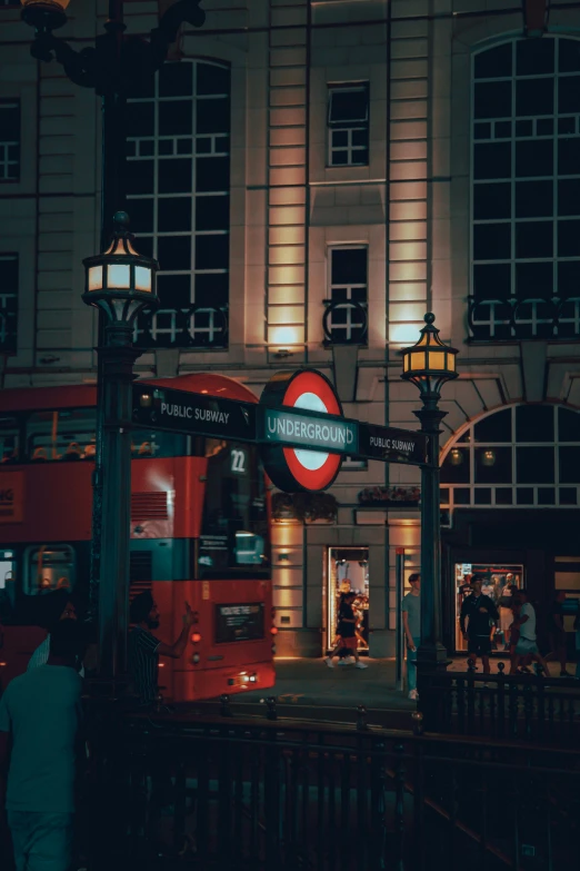 there is a red double decker bus parked next to a train station