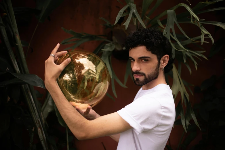 a man holding a ball in front of a tree