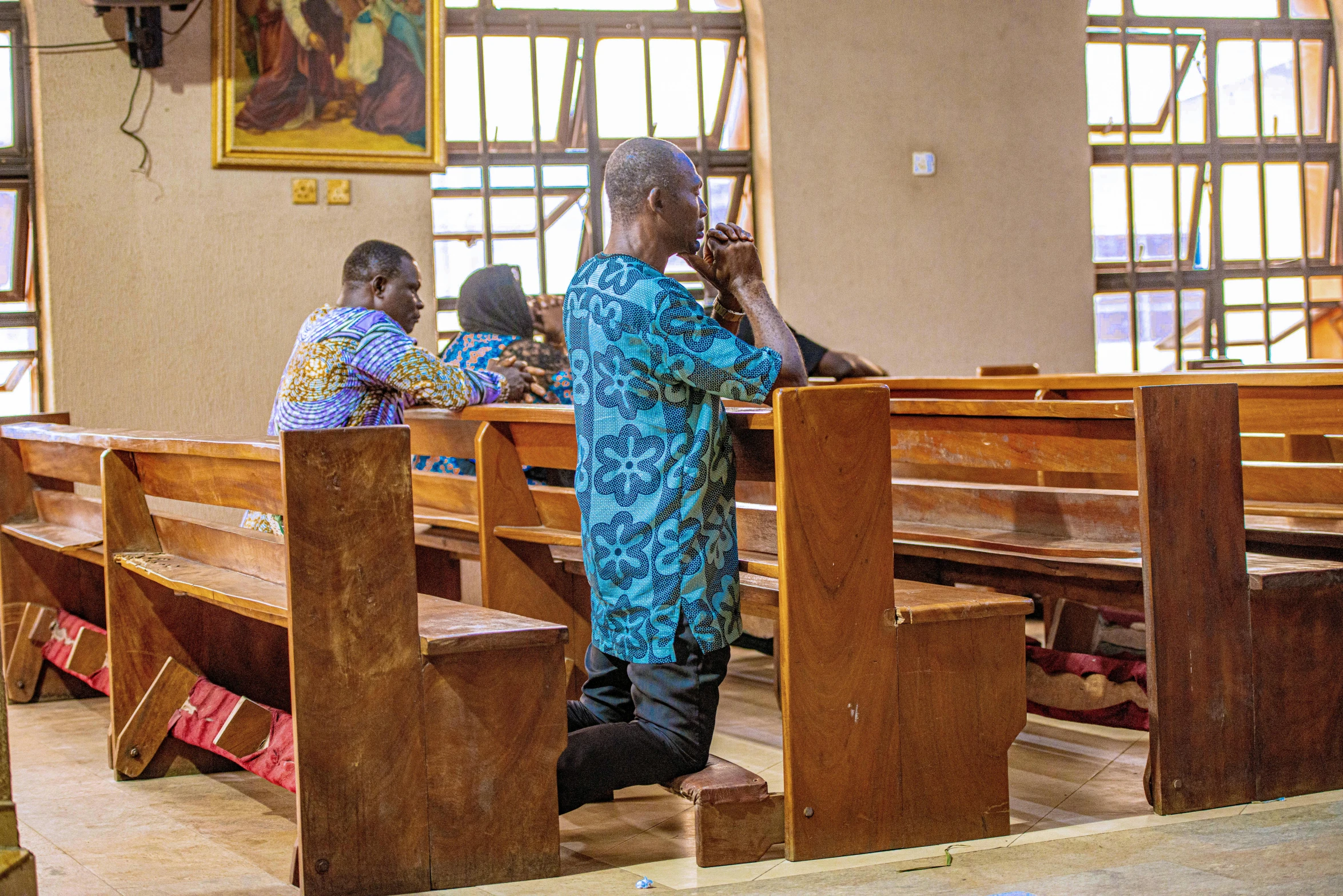 woman in blue robe praying inside of an empty church