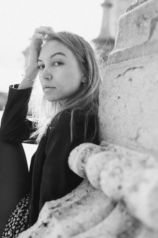 black and white pograph of woman leaning against cement wall