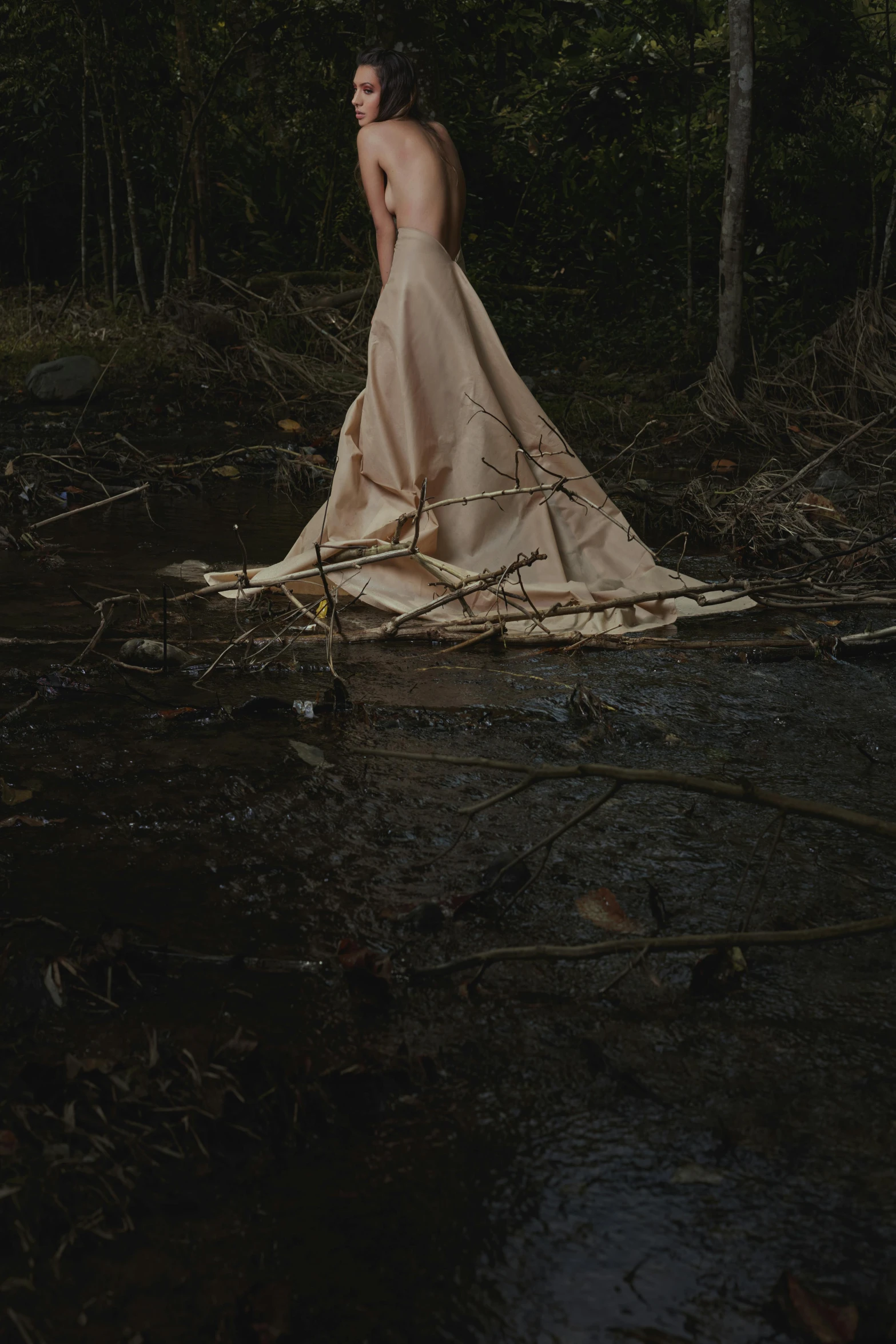 a man in a gown standing on the ground in the woods