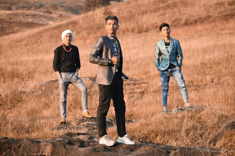 three men standing in a brown grass field