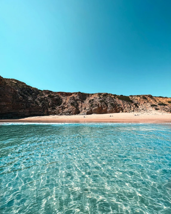 a view from the water of a beach that is near a mountain