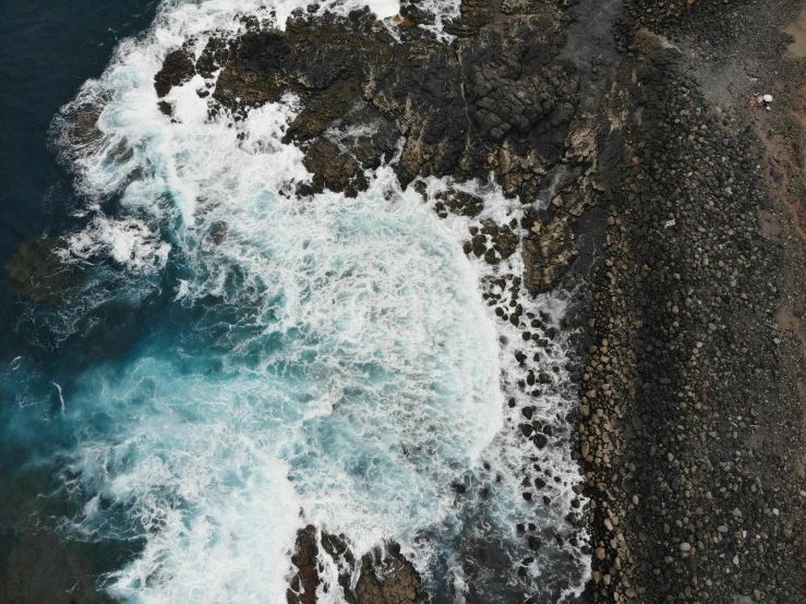 the view from a plane of the water crashing over some rocky coastline