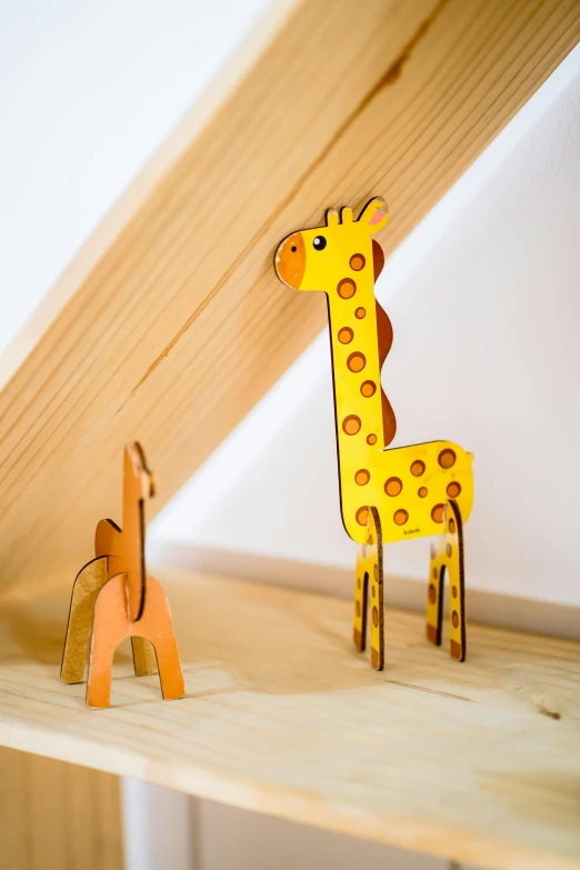 two wooden giraffe standing next to each other on a shelf