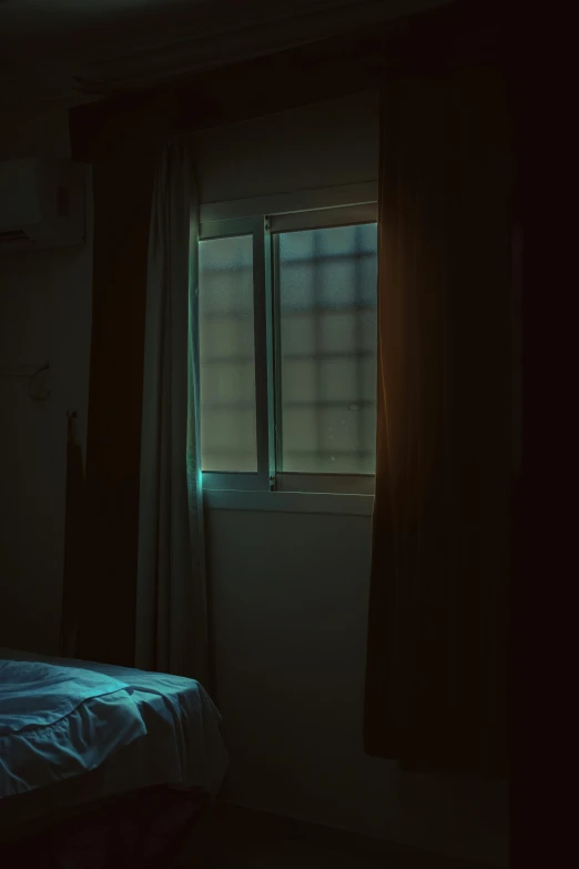 a bed sitting in the dark by an open window