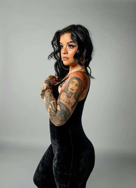 a woman in black clothes and tattoos holding a large wrist