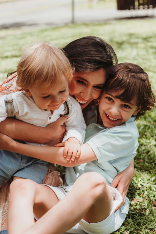 a woman with two children cuddling on the ground