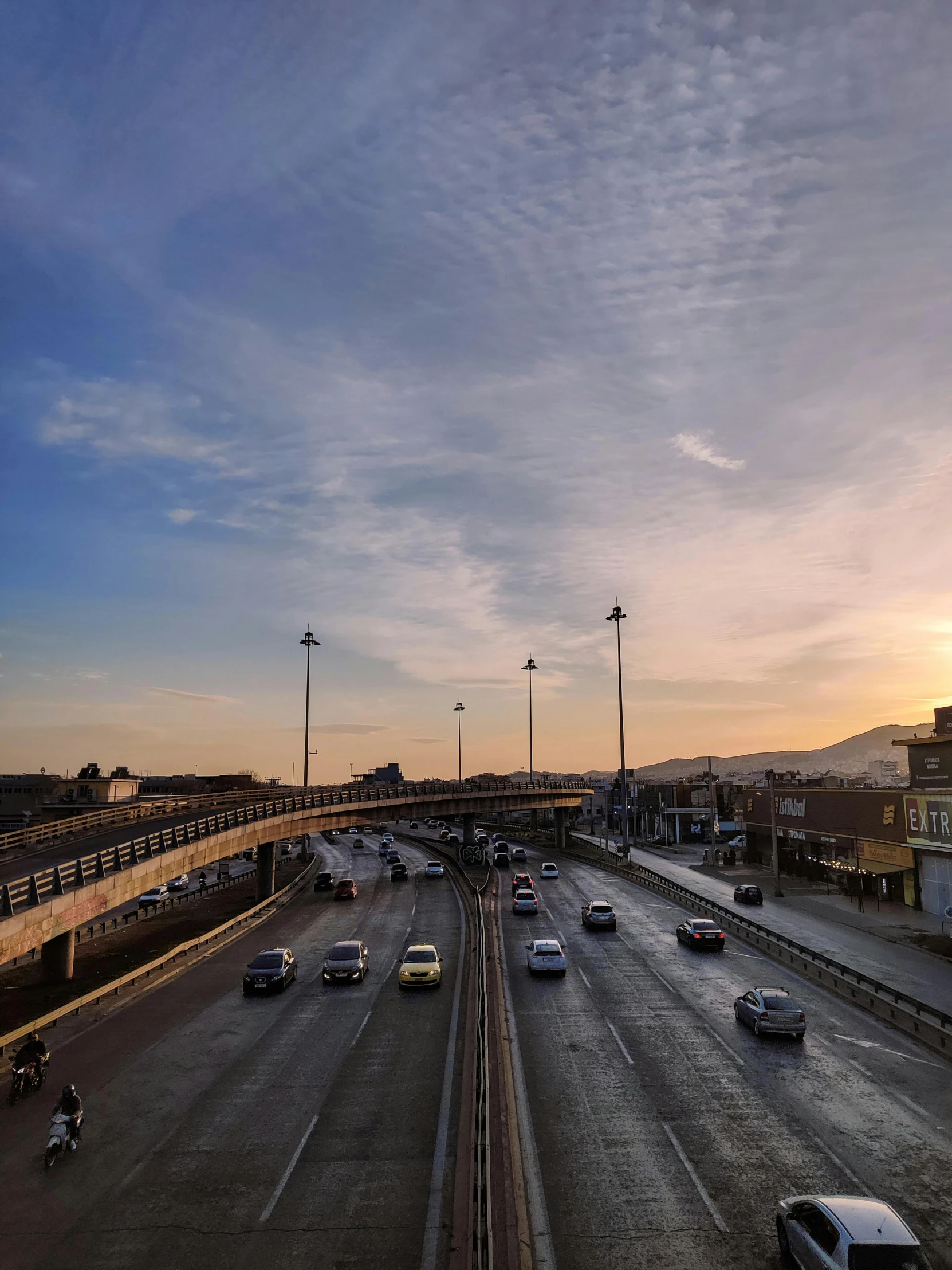 cars and people are driving on a city street at sunset