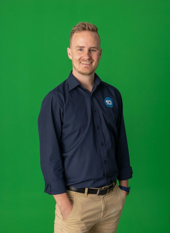 a man in a blue shirt and tan pants is smiling