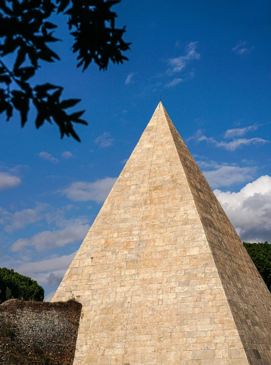 a triangular stone building under a cloudy sky