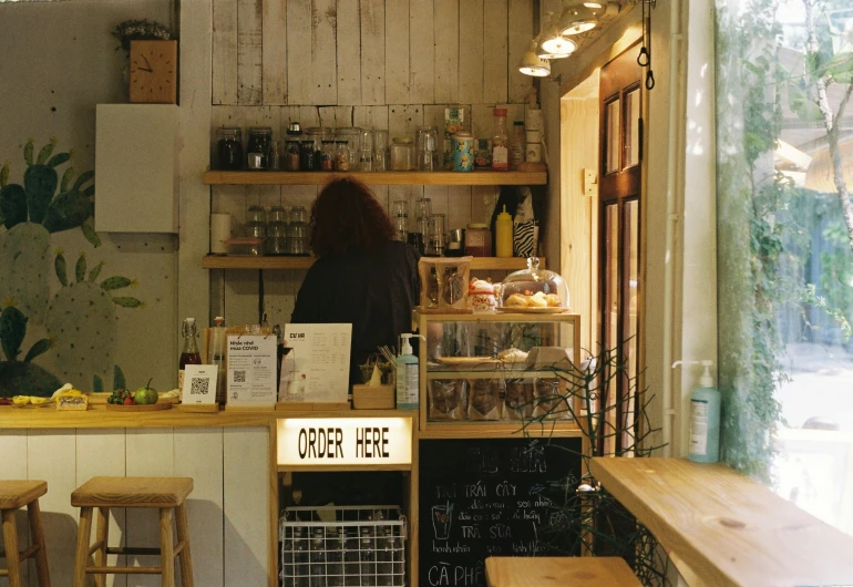 the interior of a coffee shop, with wood furniture and shelves filled with items