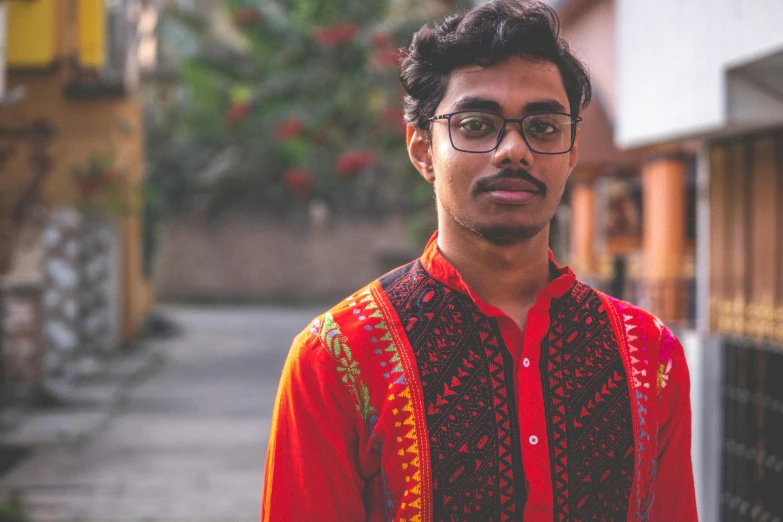 a young man in a colorfully designed shirt posing