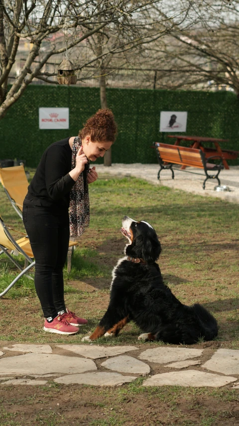 a woman sitting next to her dog in the park