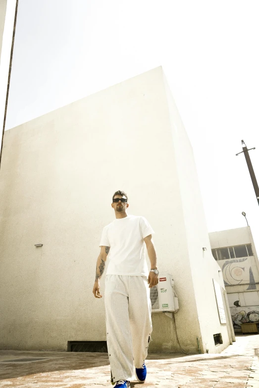 a young man is walking while wearing shades