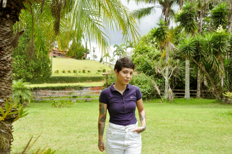 a man in purple shirt standing on grass next to trees