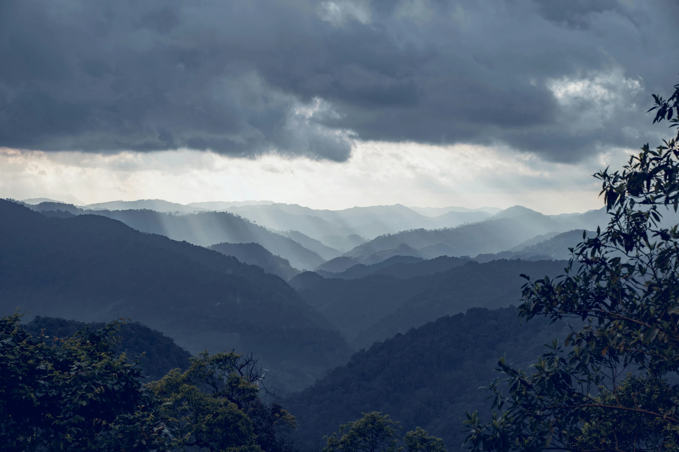 the mountains are covered in dark clouds as rain hits