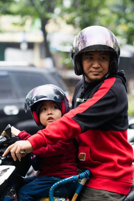 a man and a child riding on the back of a motorbike