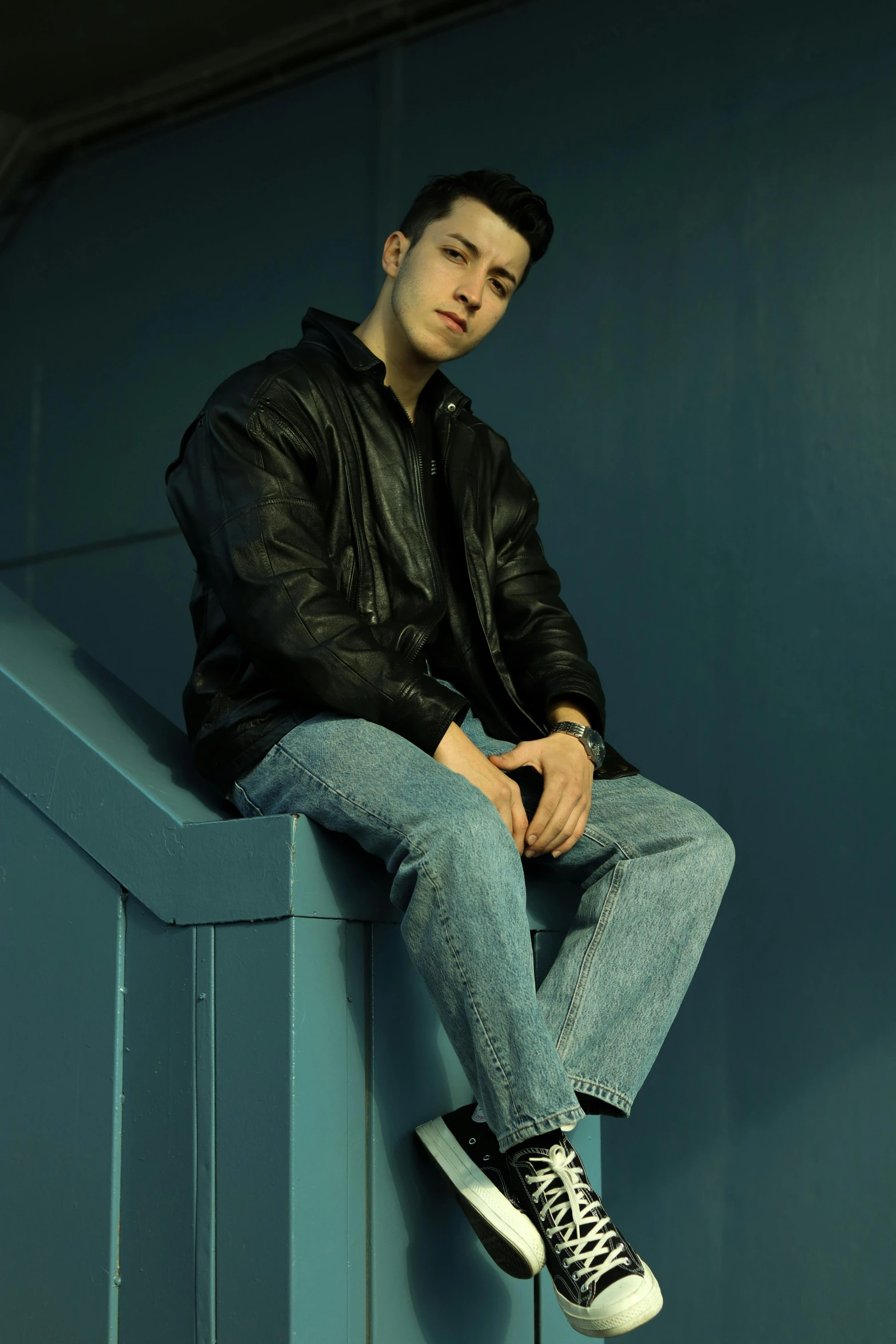 a man sitting on top of a wall near a blue door