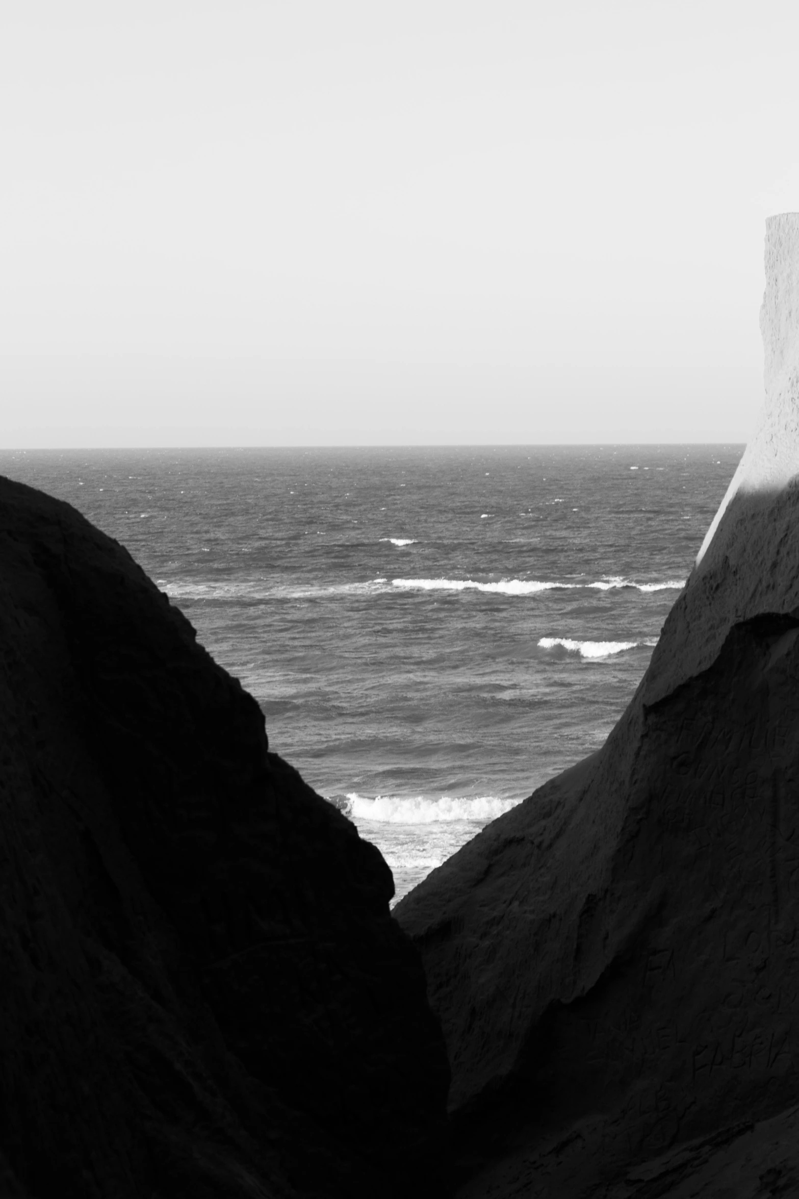 the person is standing near the beach holding a surfboard