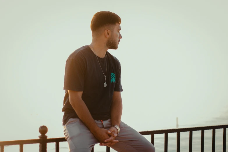 the man is sitting on a balcony looking at the water