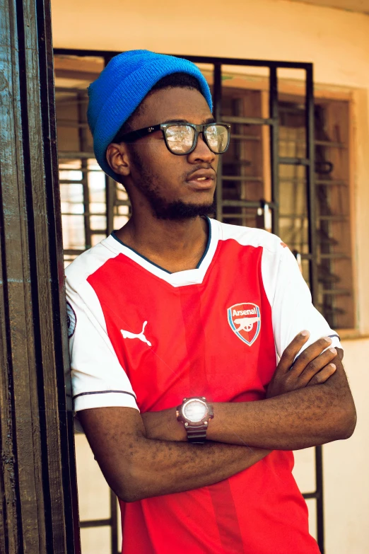 young black man in red and white shirt with his arms crossed