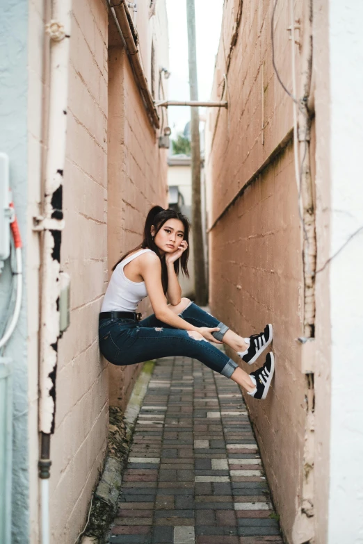 an attractive young lady leans against the wall and smiles