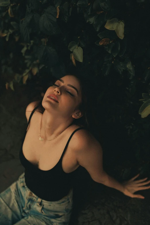 a woman sits on the ground next to a tree