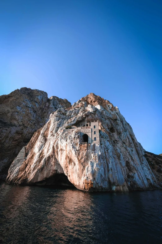 a rock sticking out of the water with a tower on top