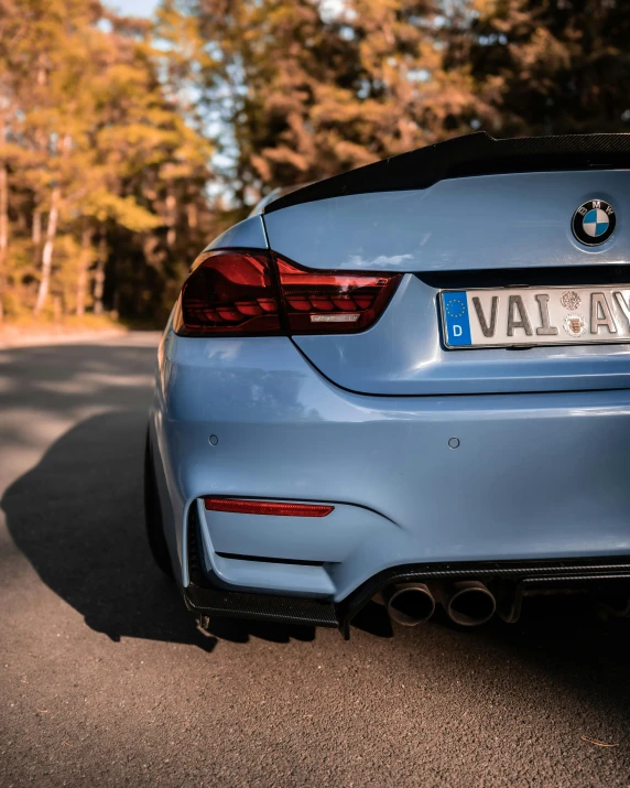 the rear end of a blue bmw coupe car parked on a street